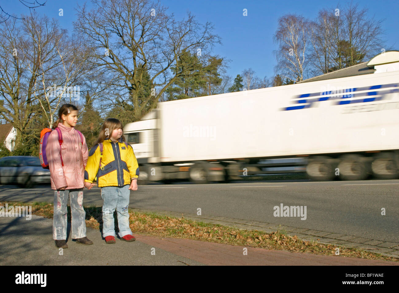 zwei junge Mädchen auf ihrem Weg zur Schule an einer Hauptstraße Stockfoto