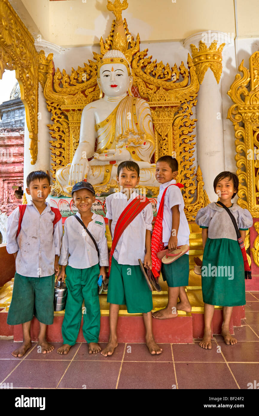 Schule Kinder posieren unter einer Buddha-Statue, Bago, Myanmar. Stockfoto