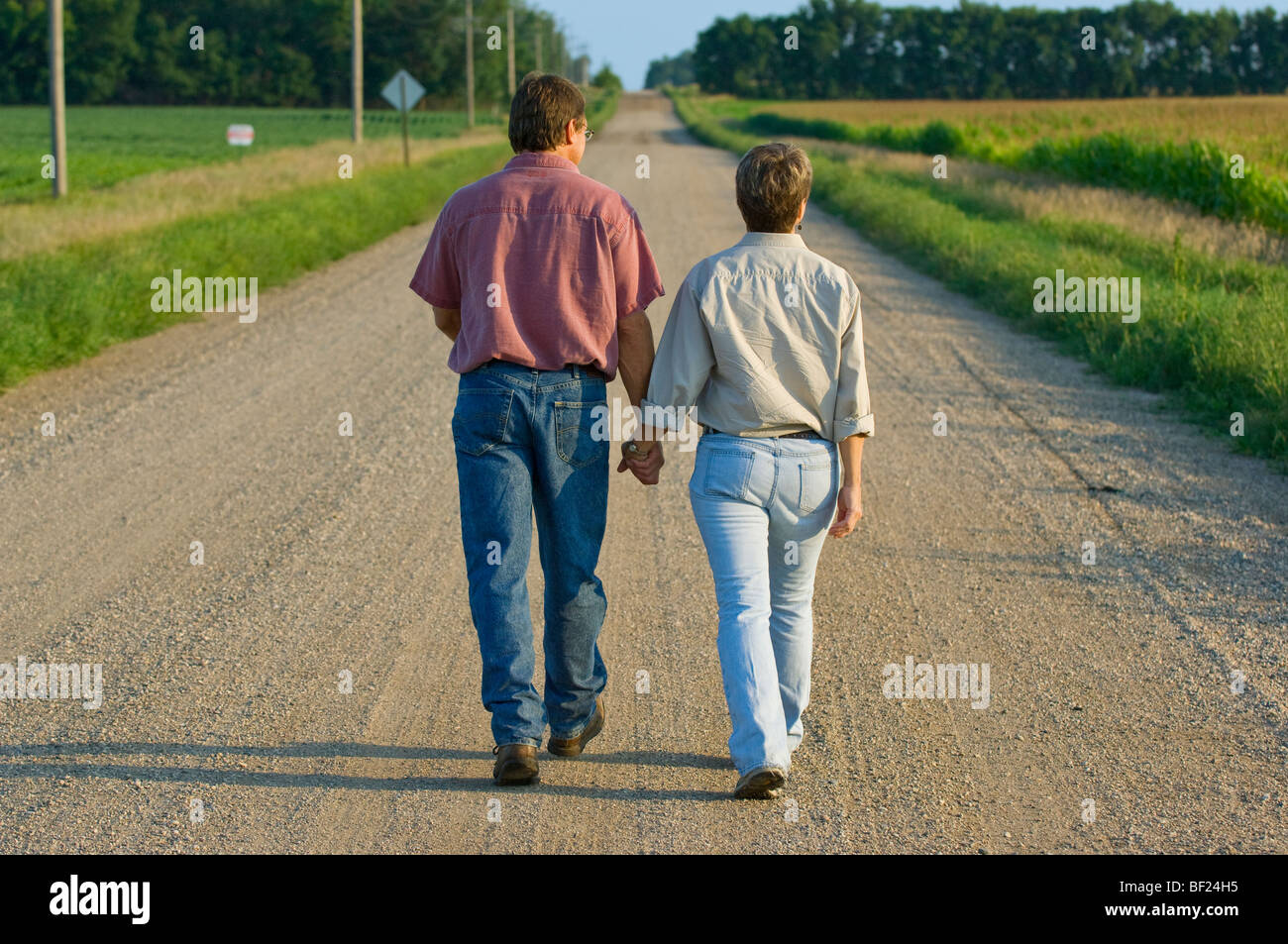 Mann und Frau Landwirte gehen Sie einem Land Straße Hand in Hand gemeinsam einige persönliche Momente / Minnesota, USA. Stockfoto