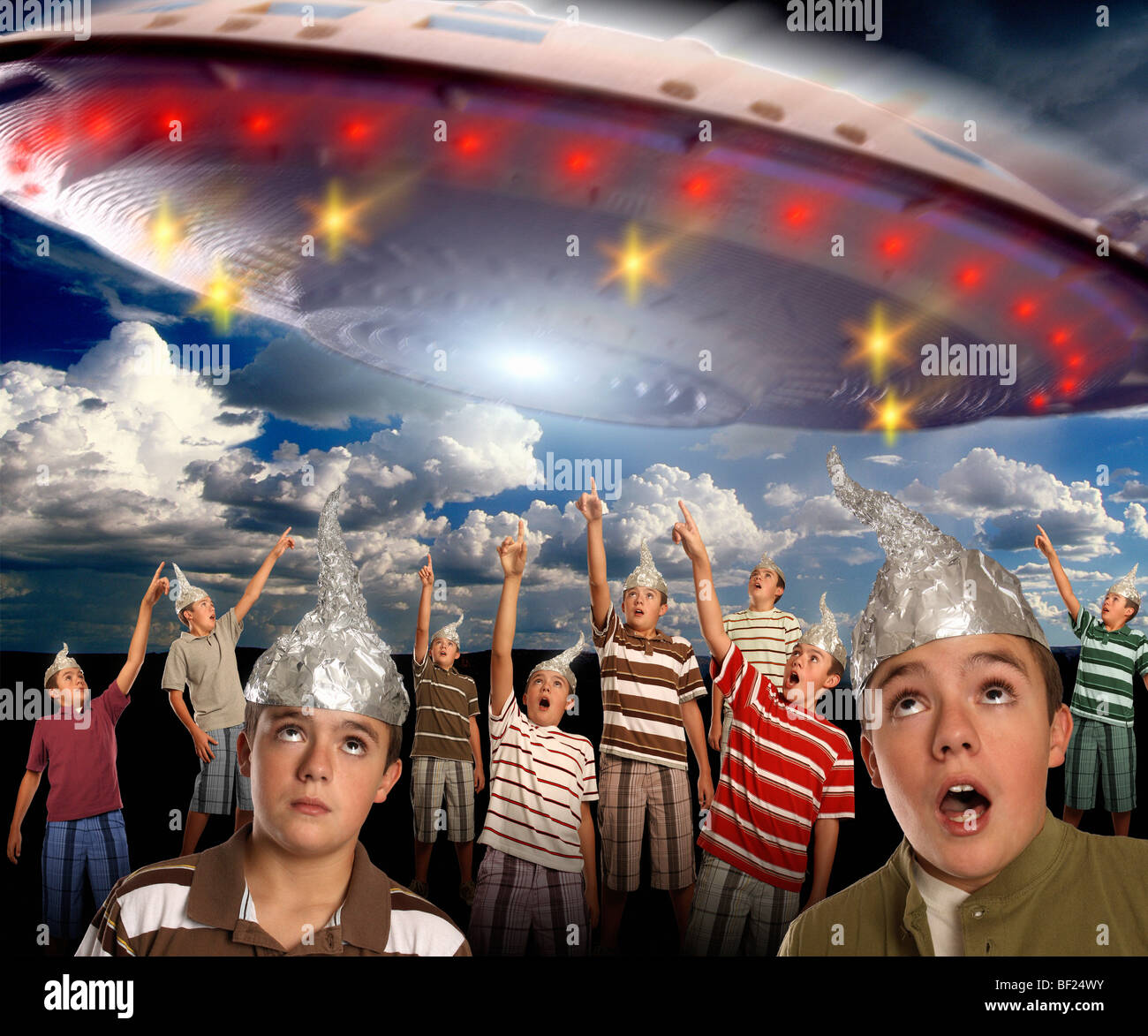 Eine Gruppe von Klonen mit Alufolie hüten verweist auf ein riesiges UFO am Himmel! Stockfoto