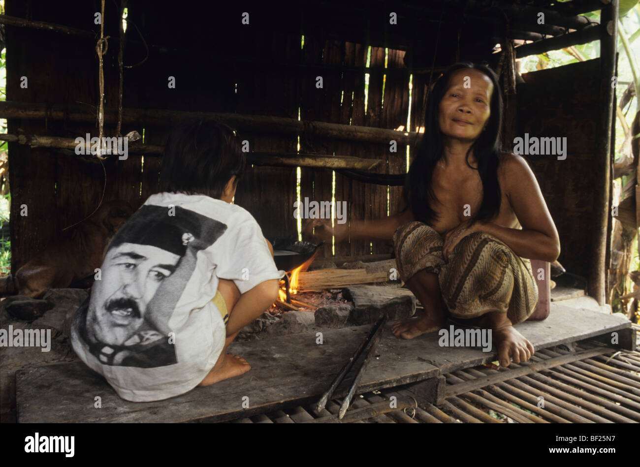 Penan in Sulap Hütte Langhaus Kochen Sago mit Sohn Saddam Hussein T-shirt tragen. Tropischen Regenwald Borneo, Malaysia Stockfoto