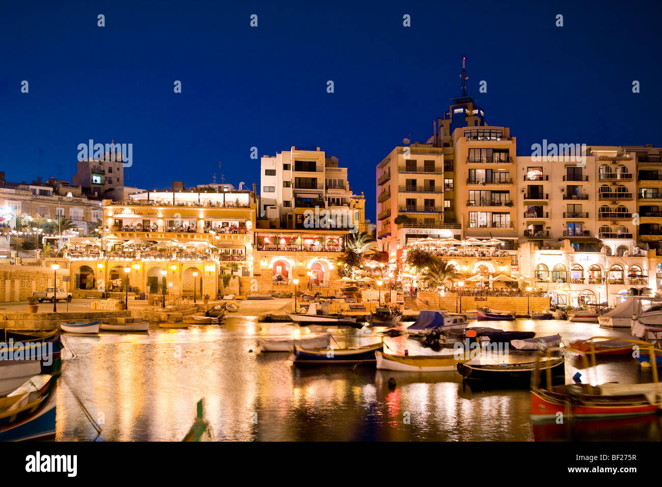 Boote in einer Bucht vor beleuchteten Häusern, Spinola Bay, St. Julian´s, Malta, Europa Stockfoto