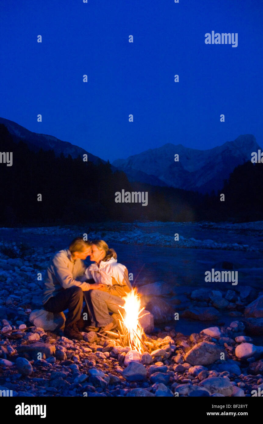 Junges Paar sitzt vor einem Lagerfeuer, küssen, Lenggries, Upper Bavaria, Bavaria, Germany Stockfoto