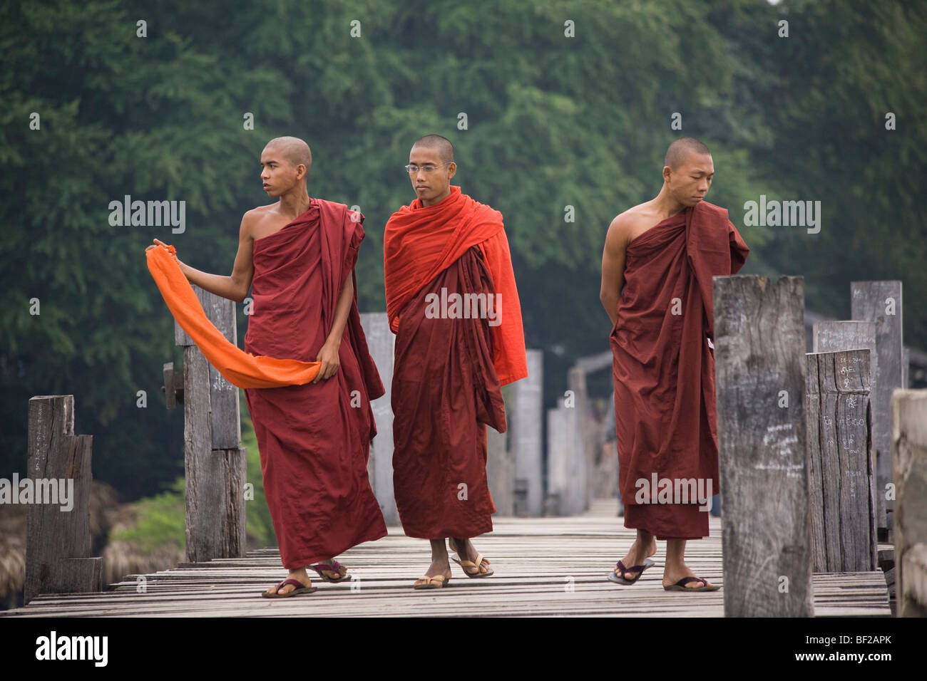 Drei junge buddhistische Mönche zu Fuß auf die U Klangkunst Bridgein Amarapura in der Nähe von Mandalay, Birma, Myanmar Stockfoto