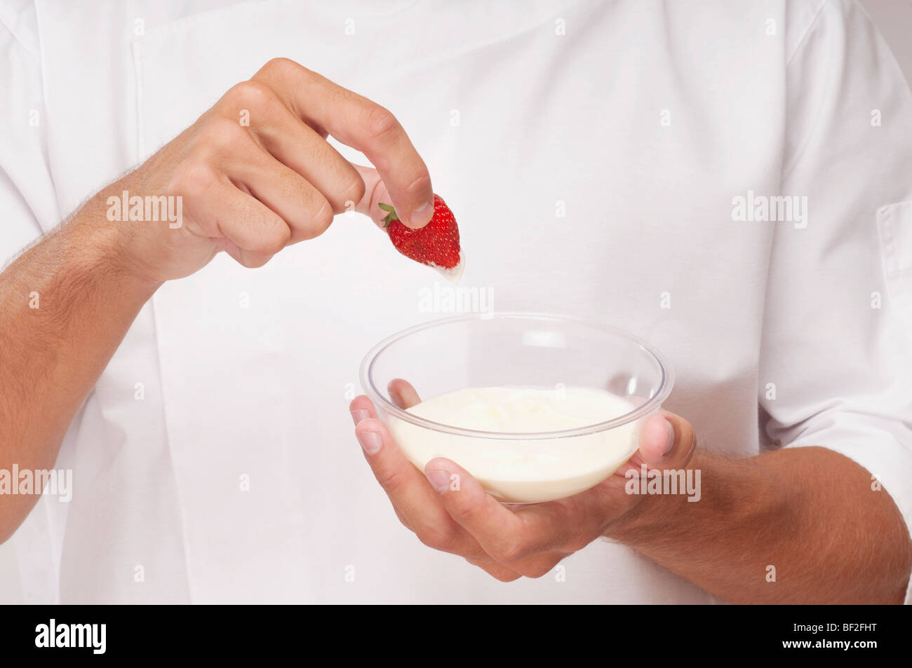 Mann eine Erdbeere in Creme Dippen Stockfoto