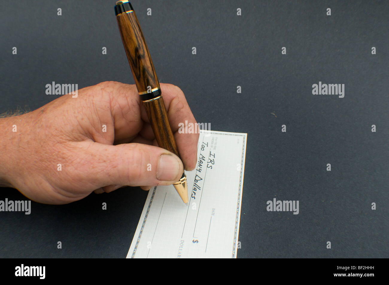 männliche Hand schreiben an IRS für zu viele Dollars zu überprüfen Stockfoto