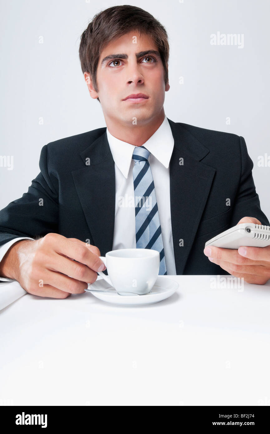Geschäftsmann hält eine Tasse Kaffee und einem Mobiltelefon Stockfoto