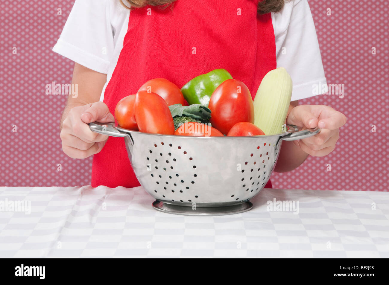 Mitte Schnittansicht eines Mädchens, das rohe Gemüse in ein Sieb hält Stockfoto