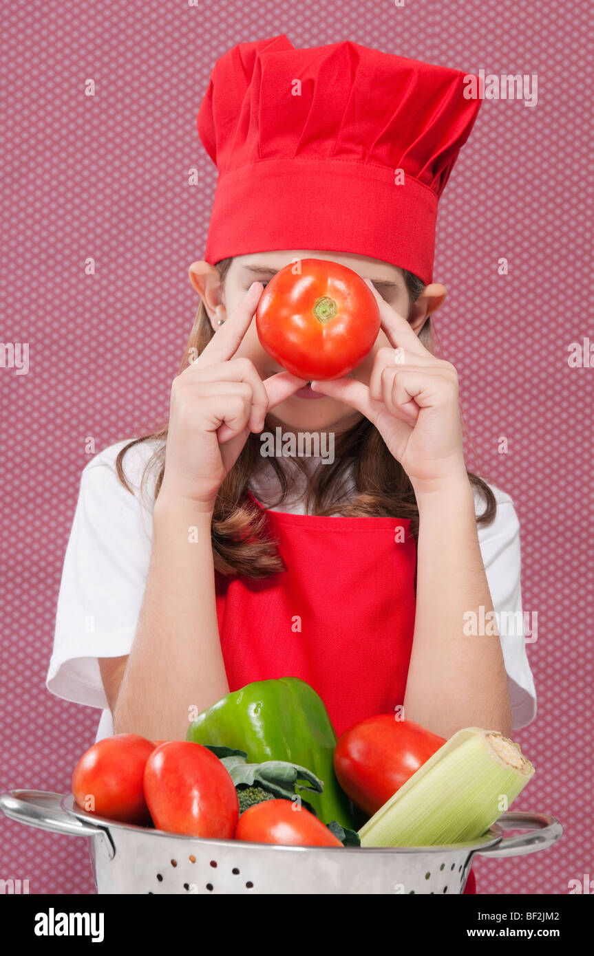 Mädchen, die eine Tomate vor ihr Gesicht halten Stockfoto