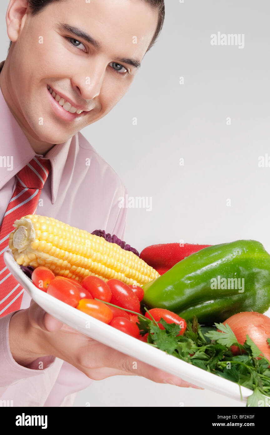 Geschäftsmann hält eine Platte mit frischem Gemüse Stockfoto