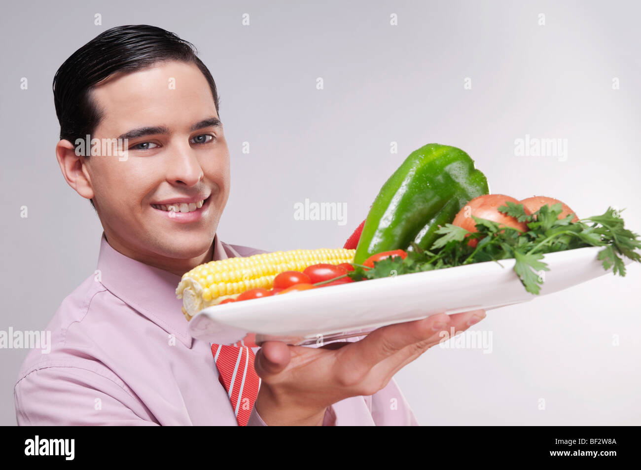 Geschäftsmann hält eine Platte mit frischem Gemüse Stockfoto