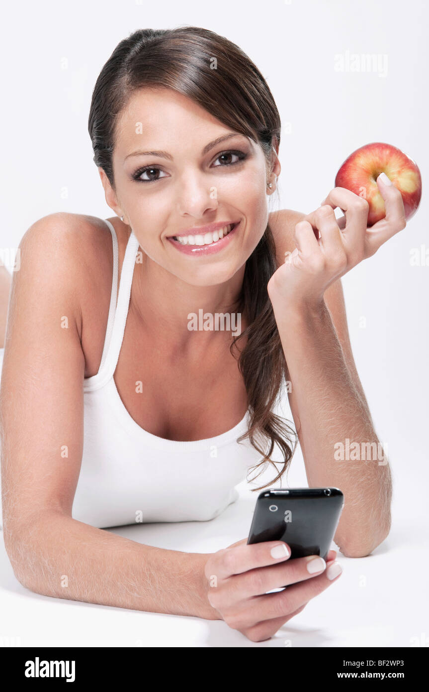 Frau hält einen roten Apfel und Benutzung eines Mobiltelefons Stockfoto