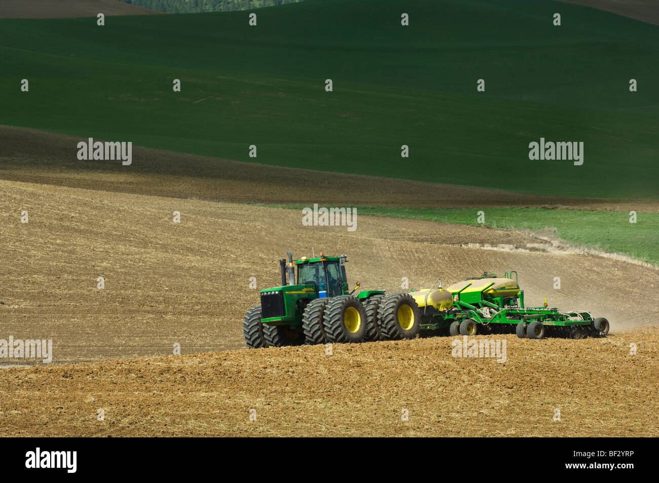 Ein John Deere Traktor und Luft Sämaschine Pflanzung Garbanzo Bohnen (Kichererbsen) in den sanften Hügeln der Palouse / Washington, USA. Stockfoto