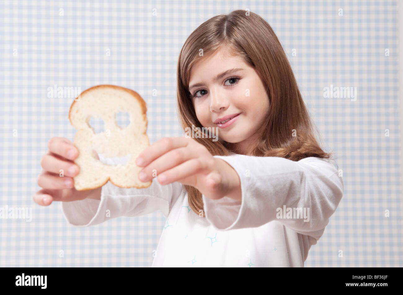 Mädchen hält eine Scheibe Brot mit Smiley-Gesicht Stockfoto