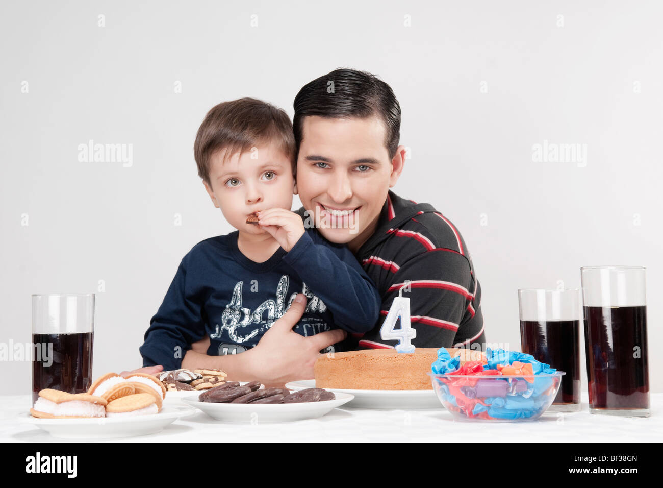 Porträt eines Mannes und seines Sohnes mit einer Geburtstagstorte vor Ihnen Stockfoto