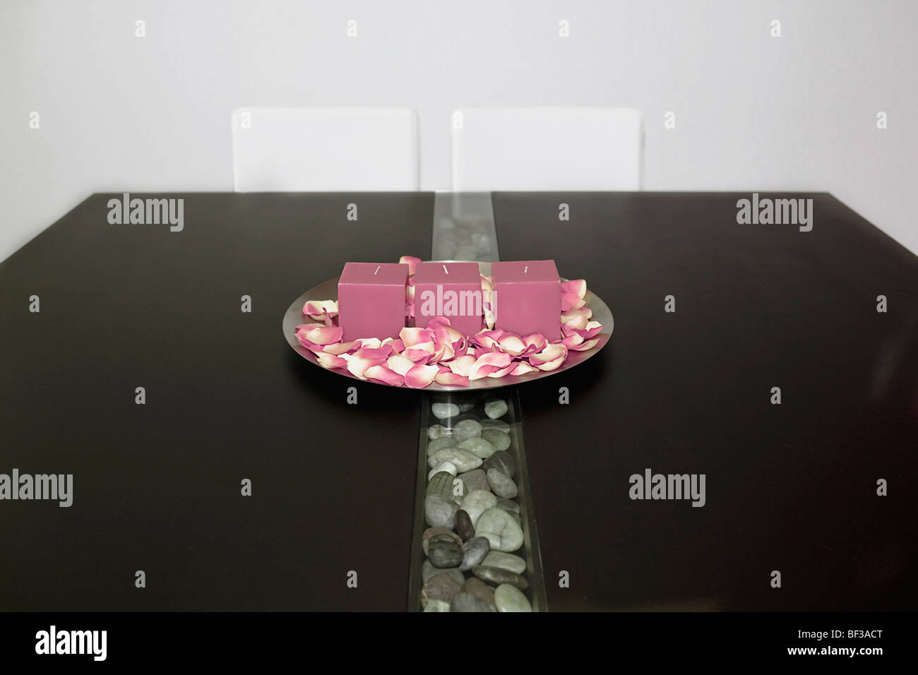 Kerzen und Rosenblätter in eine Platte auf einem Tisch Stockfoto
