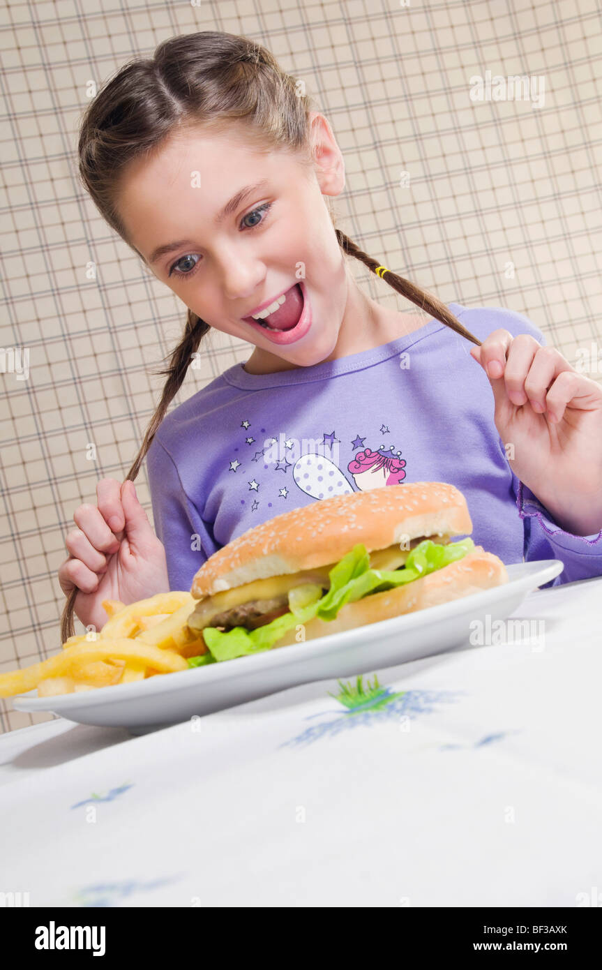 Nahaufnahme eines Mädchens Blick auf einen Teller mit Burger und Pommes frites Stockfoto