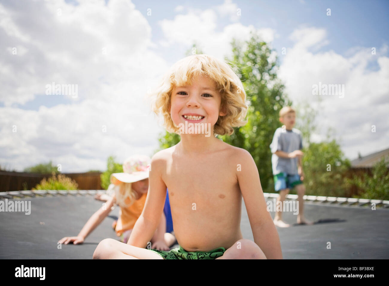 Kleiner Junge lächelnd auf Trampolin Stockfoto