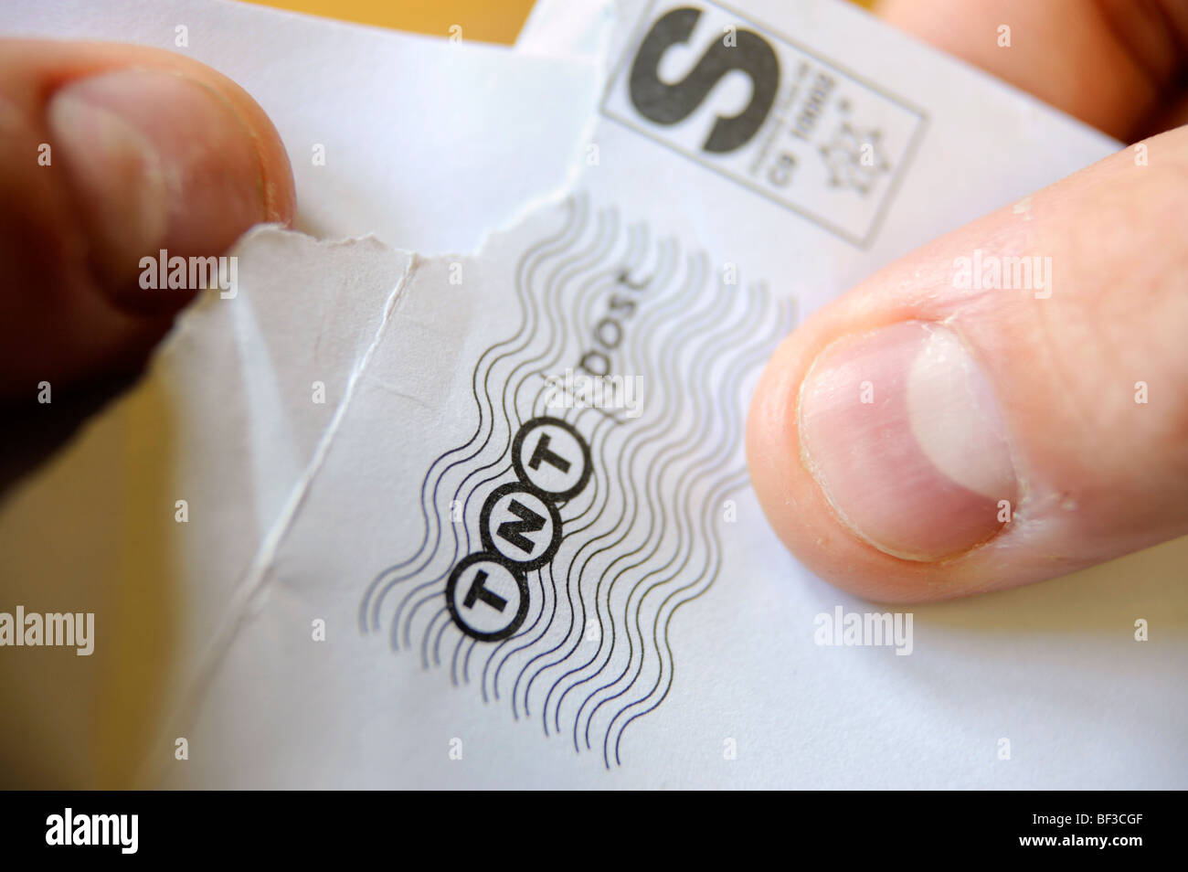 Ein Mann öffnet einen Brief von TNT geliefert Stockfoto