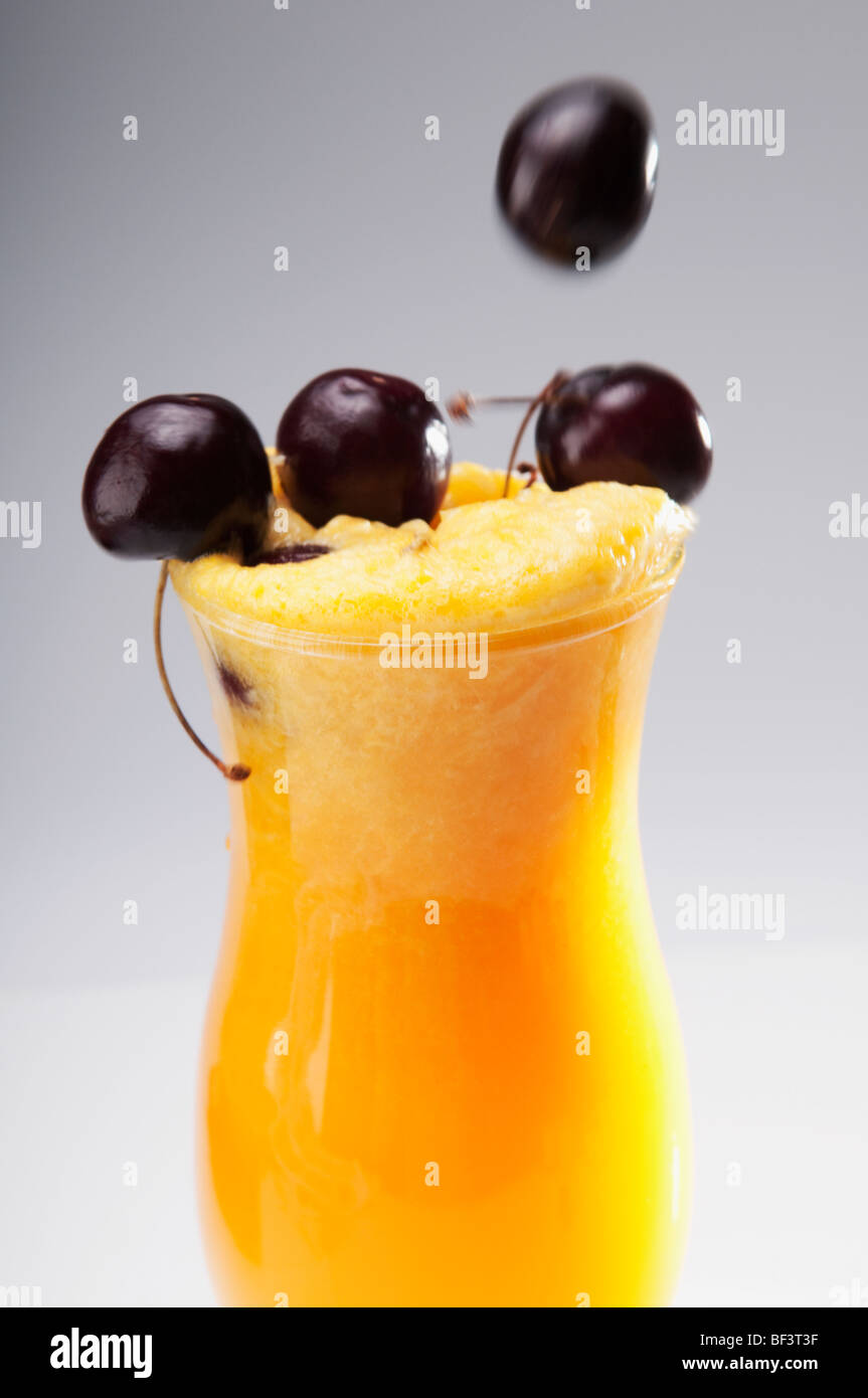 Nahaufnahme eines Glases Orangensaft mit schwarzen Kirschen Stockfoto