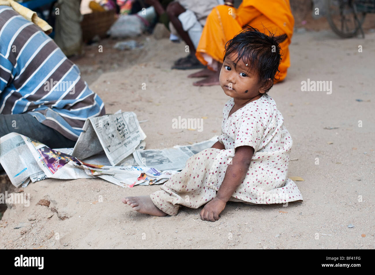 Kleine indische Mädchen sitzen auf einem indischen Straße. Puttaparthi, Andhra Pradesh, Indien Stockfoto
