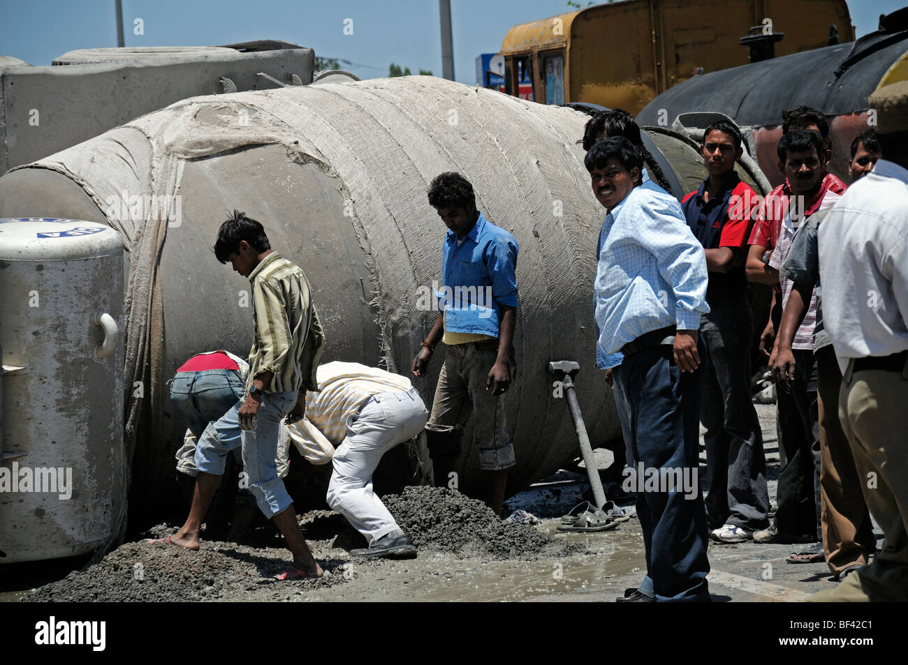 indische Männer versuchen zu retten, Rettung Zement aus einem umgestürzten Zement LKW LKW Bangalore Indien Unfall Absturz abgestürzt Stockfoto