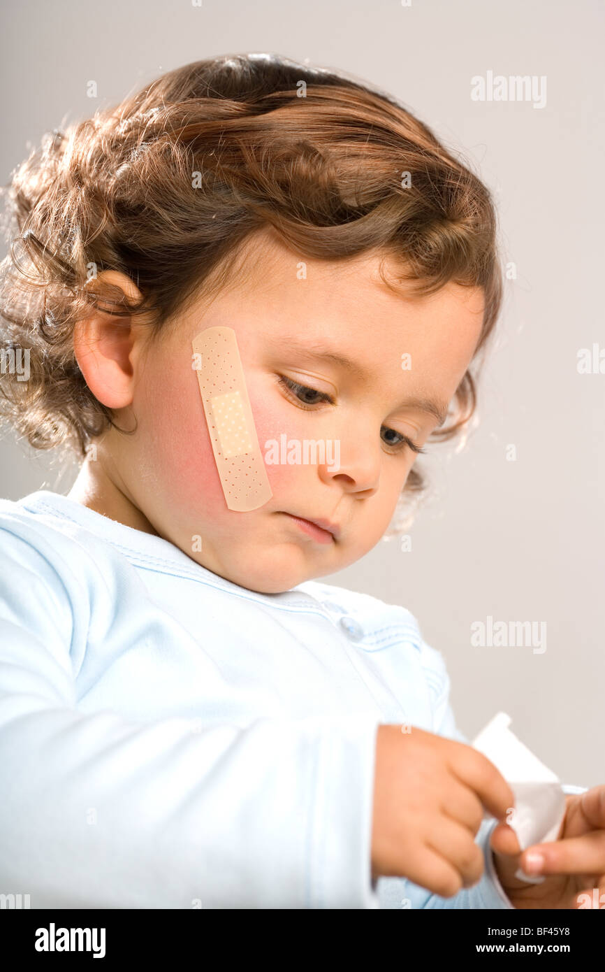 Verletzte Kleinkind mit Bandage im Gesicht Stockfoto