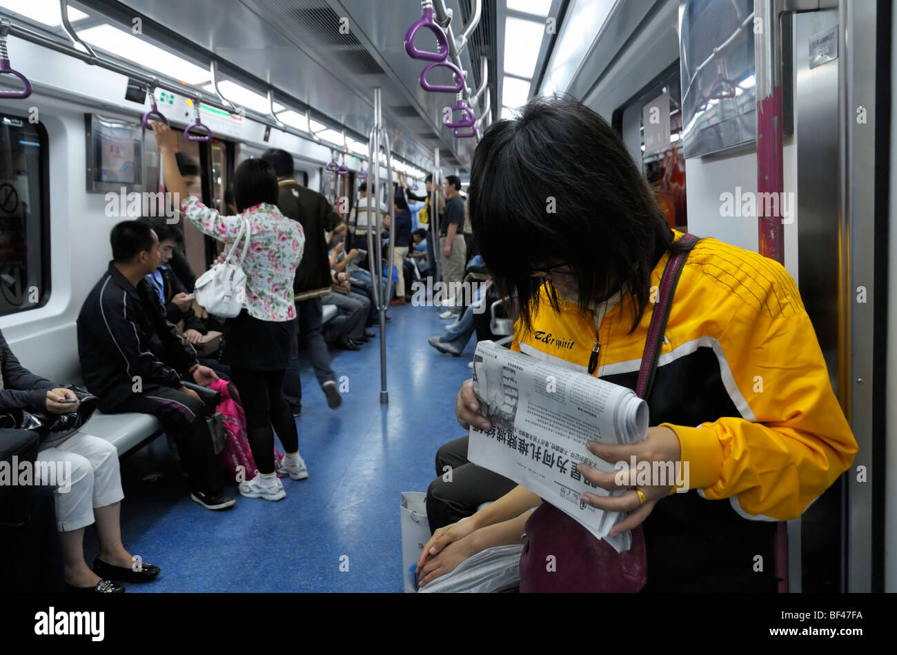 Eine weibliche Pendler eine Zeitung lesen in der U-Bahn, Beijing CN Stockfoto