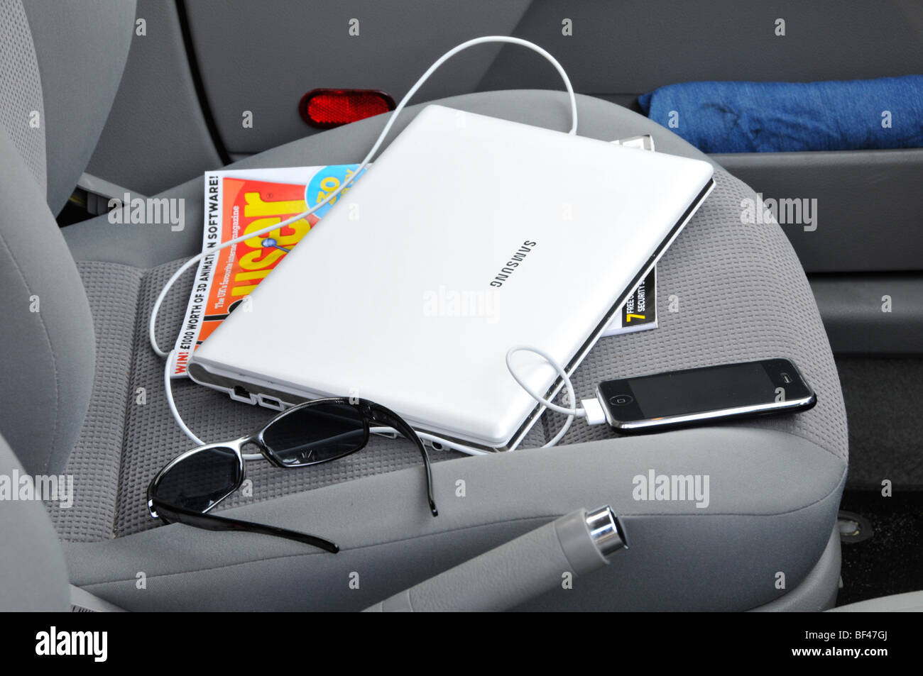 Kabel für Samsung Netbook & Connected iphone Technologie auf dem Beifahrersitz im verriegelten geparkten Auto, verlockend für Schlosserpicker England UK Stockfoto