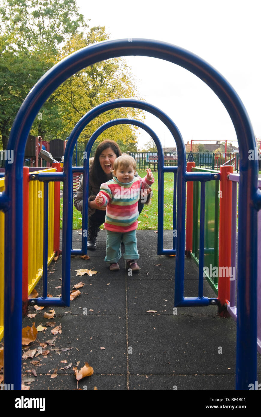 Vertikale Porträt eine junge Mutter und ihre kleine Tochter spielen zusammen in einem röhrenförmigen Labyrinth auf einen Kinderspielplatz Stockfoto