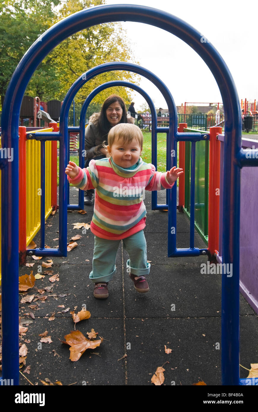 Vertikale Porträt einer jungen Mutter spielt mit ihre kleine Tochter auf einem rohrförmigen Labyrinth an ein Kinderspielplatz zur Verfügung. Stockfoto