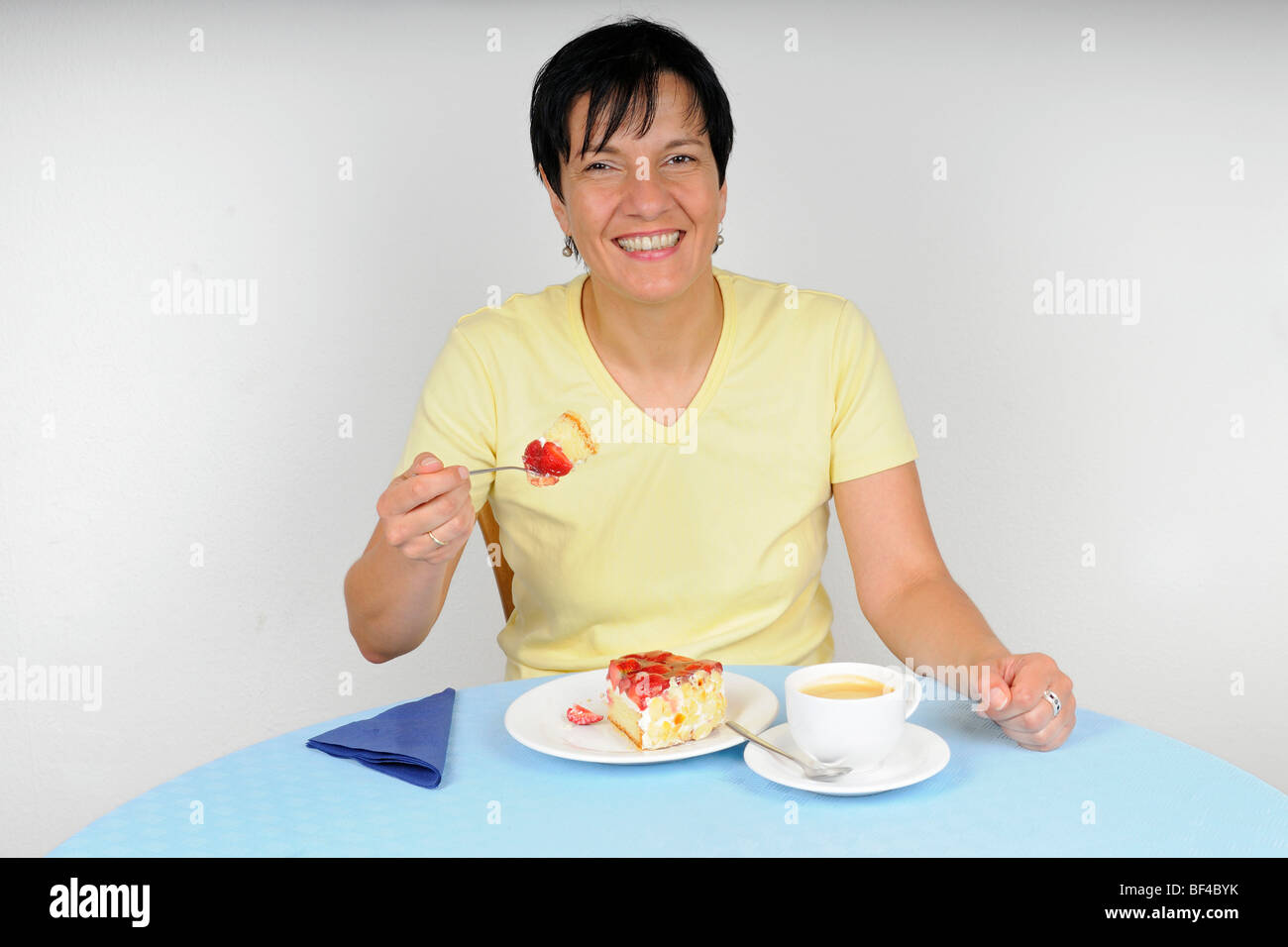 Frau an einem Tisch sitzen und genießen Sie Kaffee und Kuchen Stockfoto