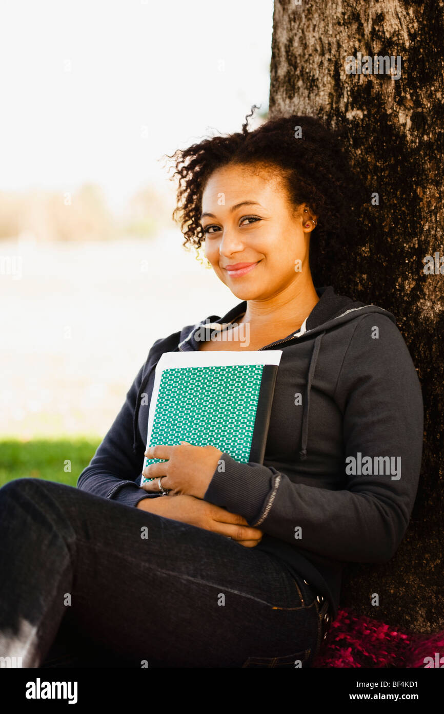 Afrikanische Frau mit Buch an Baum gelehnt Stockfoto