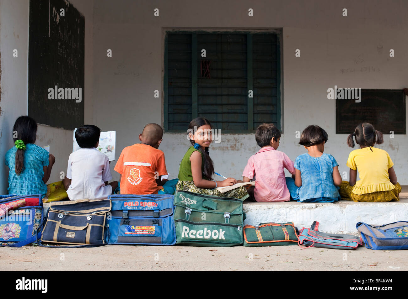 Indian School Kinder außerhalb ihrer ländlichen Dorfschule sitzen. Andhra Pradesh, Indien Stockfoto
