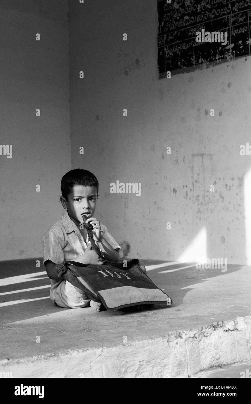 Indian School Boy außerhalb seiner Schule sitzen. Andhra Pradesh, Indien. Schwarzweiß Stockfoto