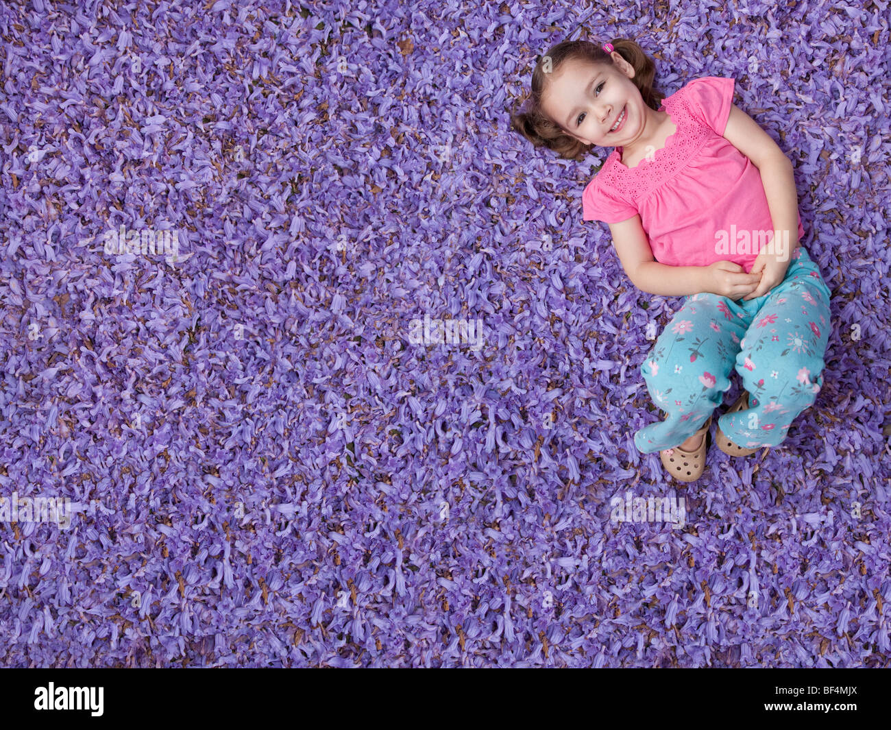 Junges Mädchen auf Bett lila Blumen Stockfoto