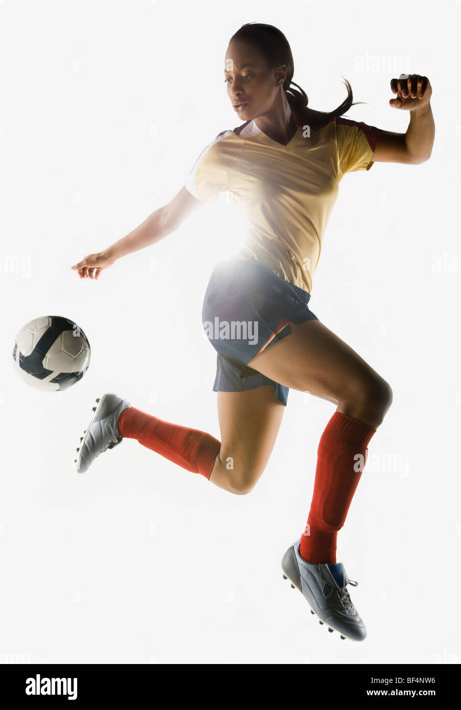 Gemischte Rassen Fußballspieler treten Fußball in der Luft Stockfoto