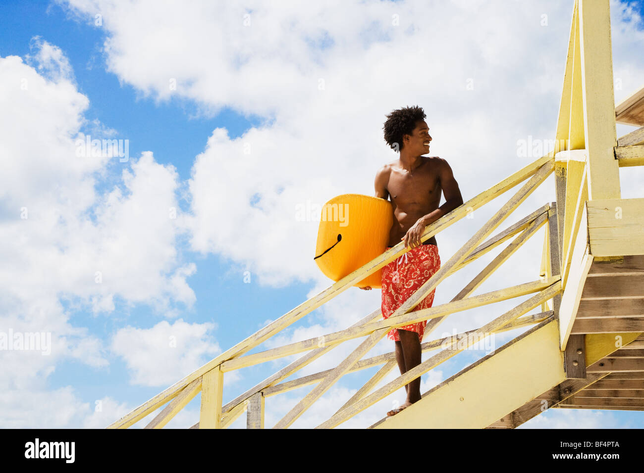 Afrikanischer Mann Rettungsschwimmer Hütte Rampe Bodyboard festhalten Stockfoto