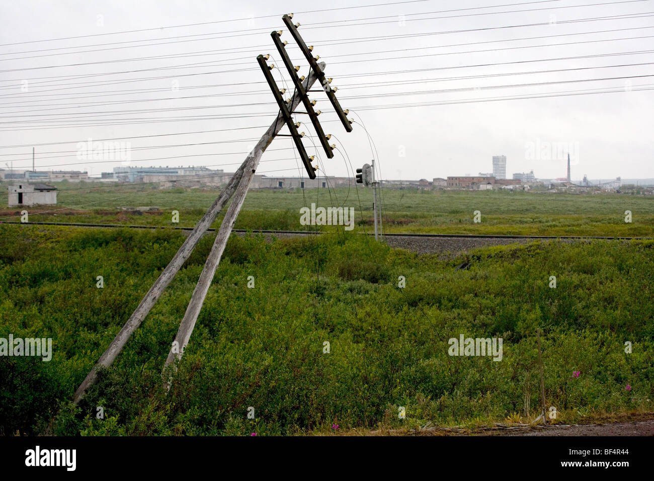 Gefallenen Telegraphenmast mit industriellen Gebäuden und Schornsteine auf dem Horizont, Ural, arktischen Russland Stockfoto