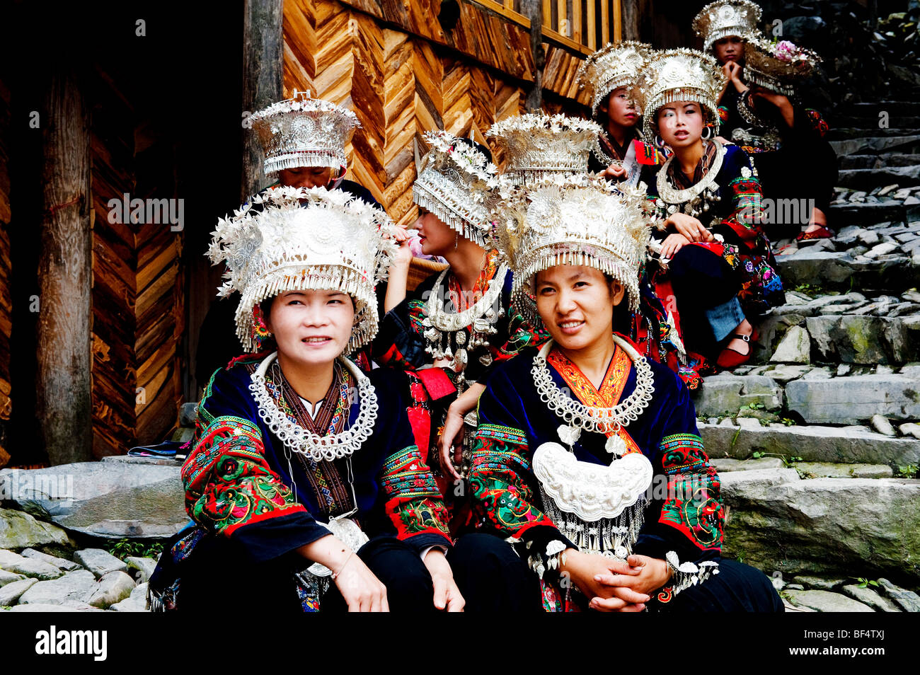 Miao junge Frauen sitzen auf gepflasterten Treppen, Xijiang Miao Dorf, Leishan Grafschaft, Stadt Kaili, Guizhou Provinz, China Stockfoto