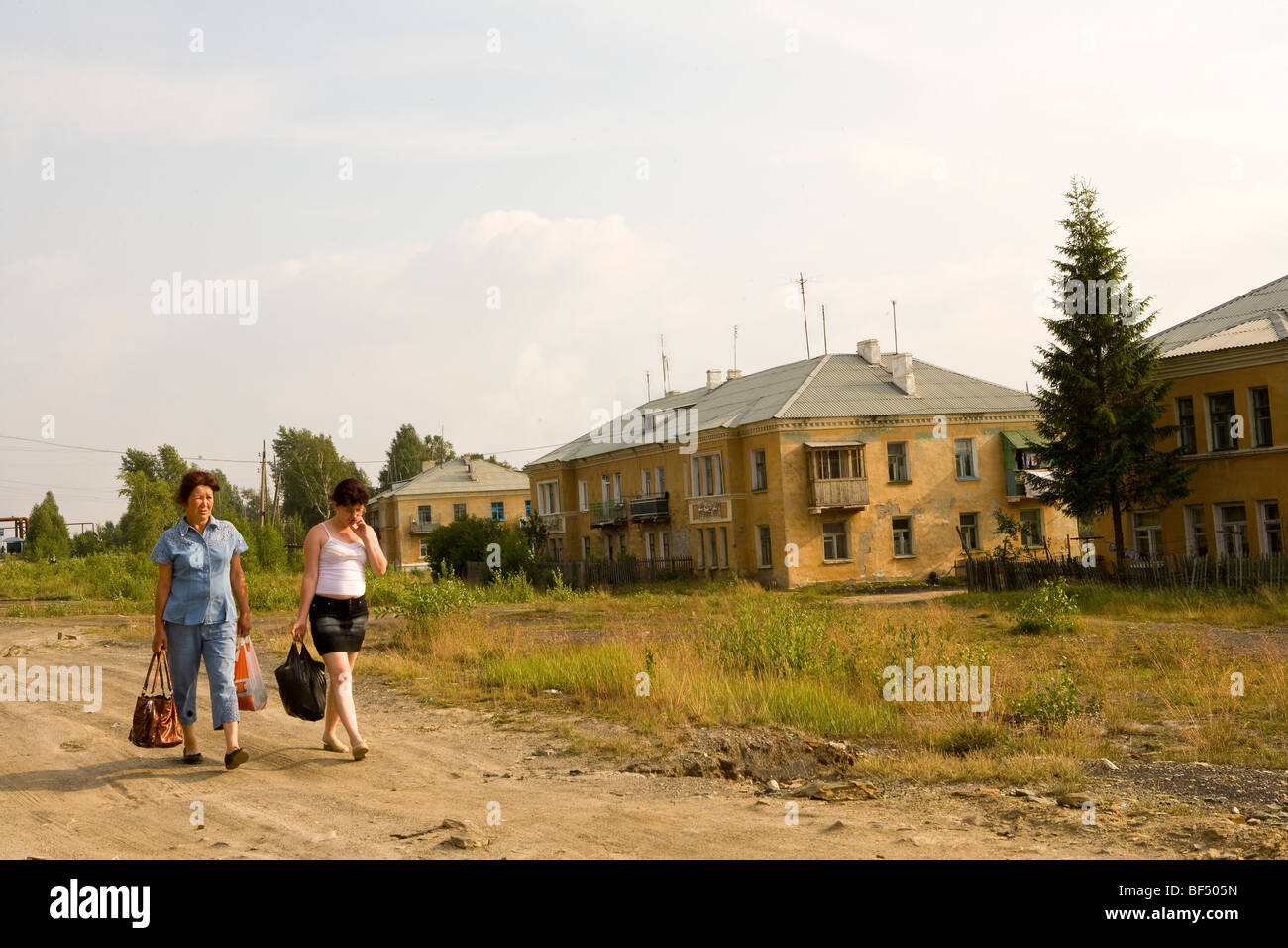 Frauen mit Einkaufstaschen zu Dirt Track von Wohnblocks, Karabash, Russland Stockfoto