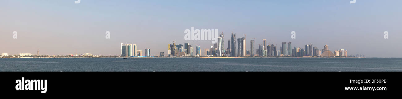 Ein Blick auf die Skyline des neuen Bezirk von Doha, Katar, an einem Morgen etwas dunstig. Genähte Panorama. Logos und Werbung sichtbar. Stockfoto