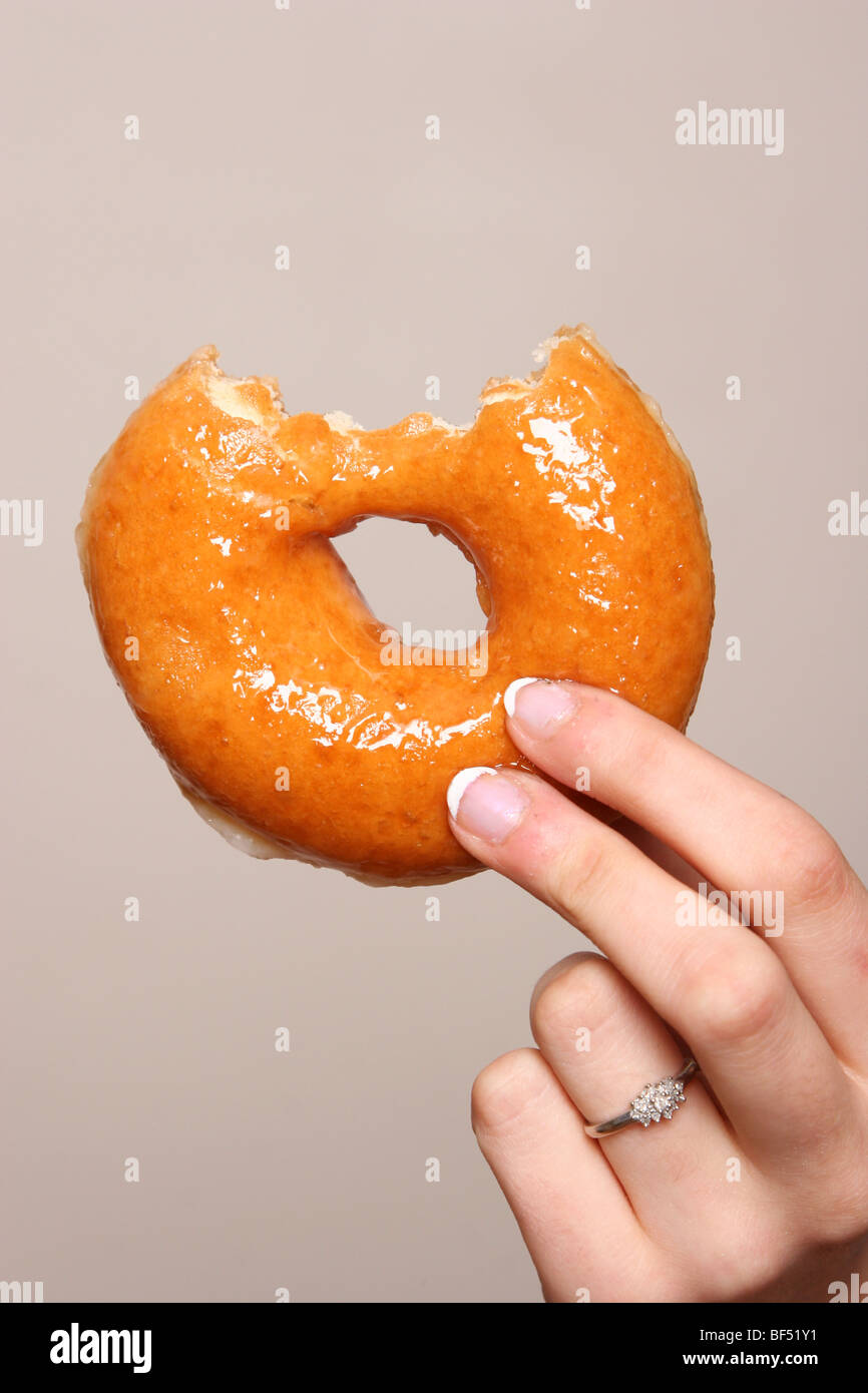 Hand, die eine Hälfte gegessen Teig-Nuss Stockfoto