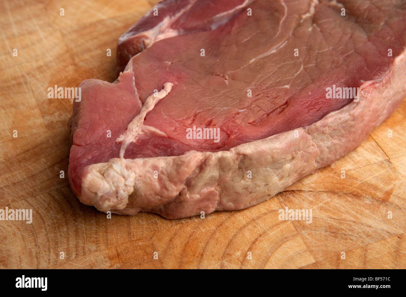 Nahaufnahme des Fettrandes ein rohes Stück Hüfte Steak vom organischen Longhorn irischen Kühe auf einem hölzernen Metzger-block Stockfoto