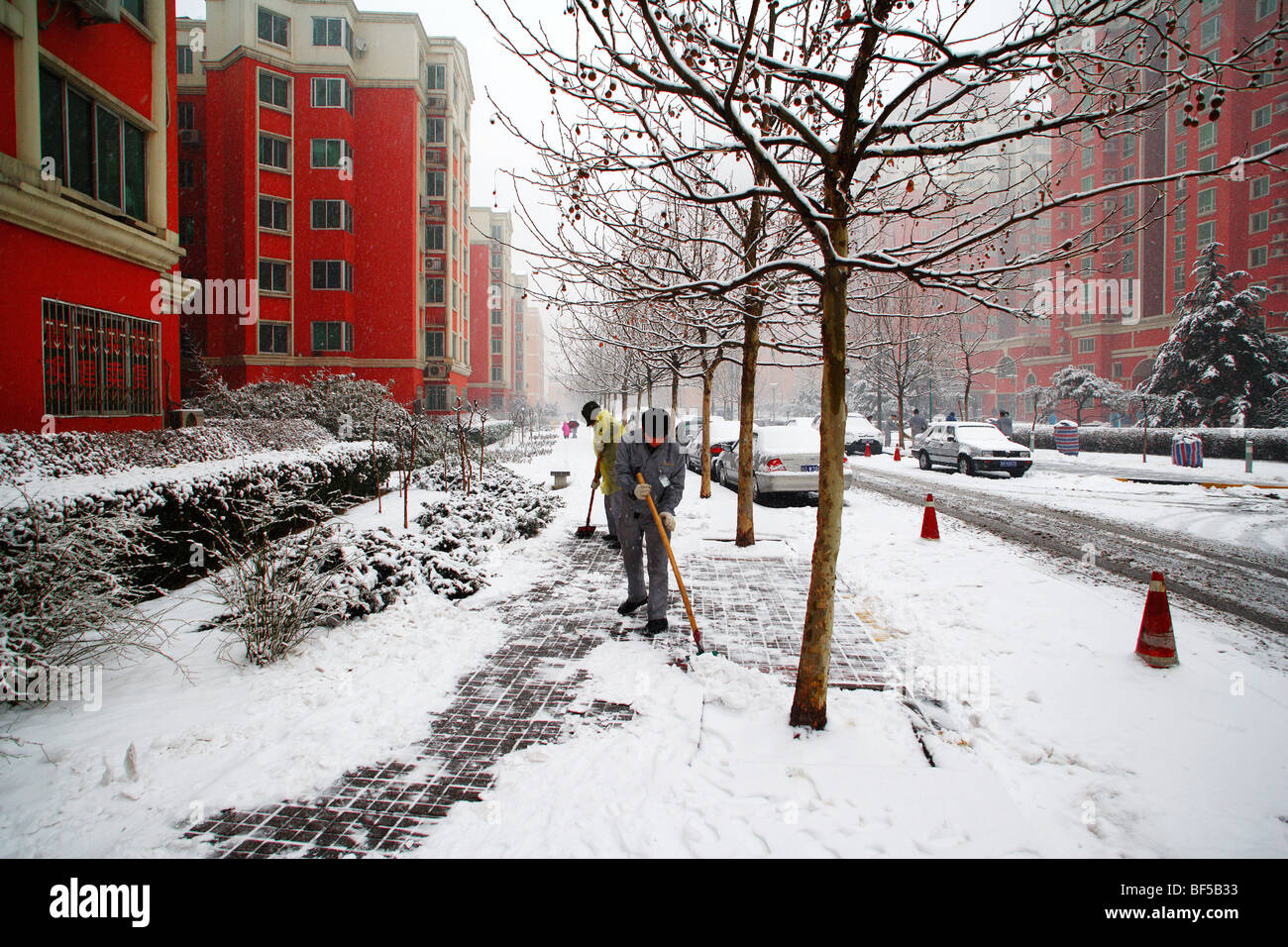 Hausmeister Entrümpelung Schnee am Morgen in Luxusapartment-Komplex, Peking, China Stockfoto