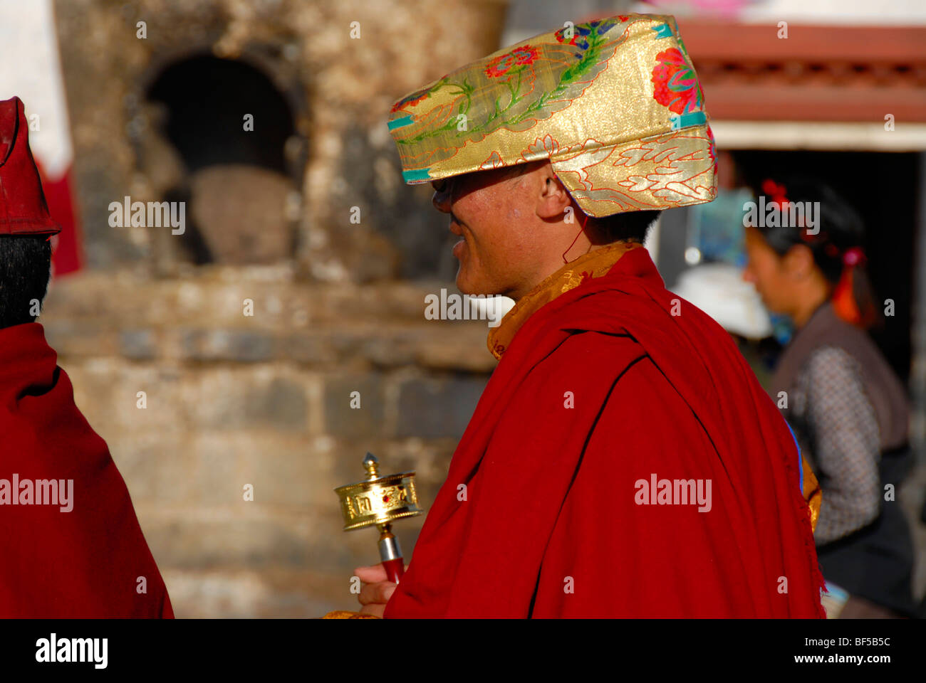 Tibetischen Buddhismus, Kora Pilger, Mönch gekleidet in roten Roben mit einer goldenen Kappe und eine Gebetsmühle unterwegs, um die Barkhor, Jokh Stockfoto