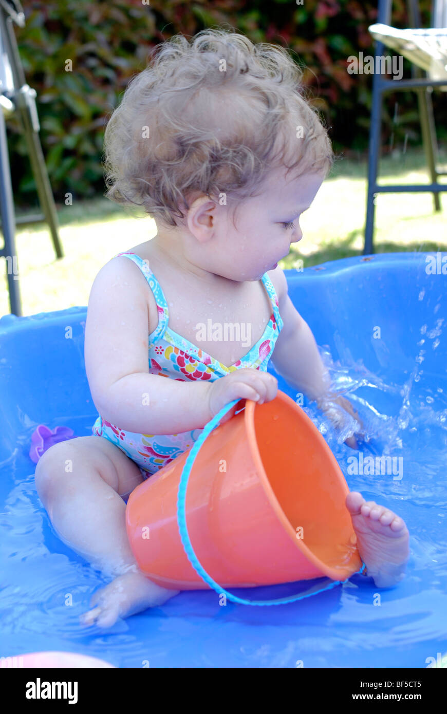 Kleinkind mit Wasser im Planschbecken spielen. 16 Monate altes Mädchen. Stockfoto