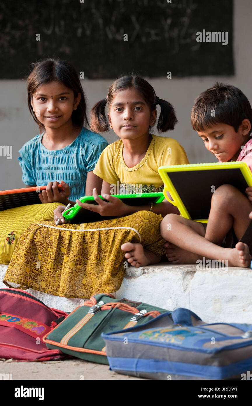 Indian School Kinder sitzen außerhalb ihrer Schule schreiben auf der Schiefertafel. Andhra Pradesh, Indien Stockfoto