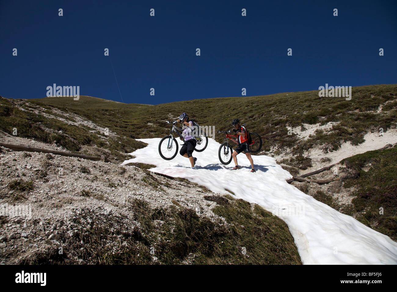 Mountain-Bike-Fahrer mit Fahrrädern über ein Schneefeld auf der Strecke zwischen dem Kreuzjoch Bergschlucht, Ju Dles Cacagnar Stockfoto