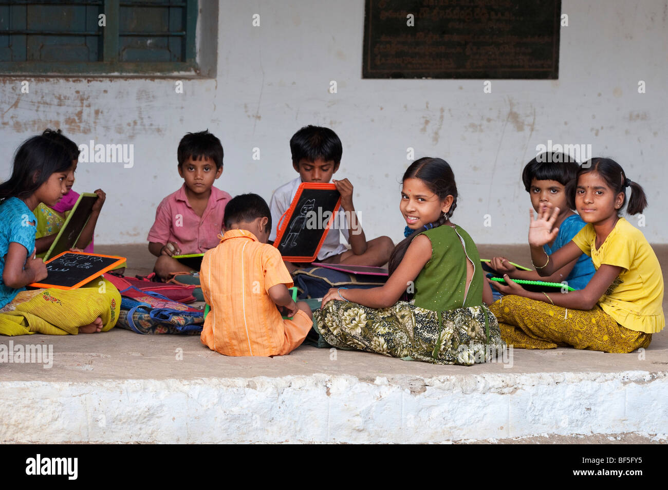 Indian School Kinder sitzen außerhalb ihrer Schule schreiben auf der Schiefertafel. Andhra Pradesh, Indien Stockfoto